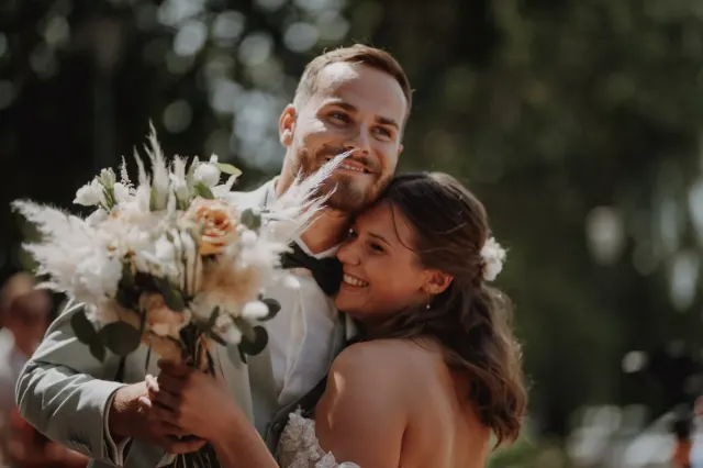 Mariés enlacés et rieurs, bouquet de fleurs séchées à la main, après la découverte à la mairie d'Houplines