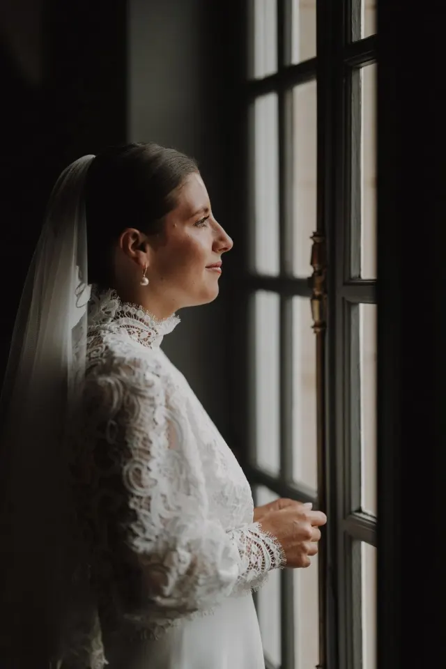 Mariée en dentelle ancienne à la fenêtre, préparatifs au Clos Barthélémy à Eterpigny