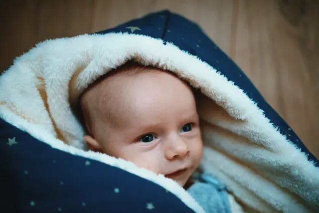 Nouveau-né emmitouflé dans une couverture étoilée, séance naissance à domicile dans les Flandres