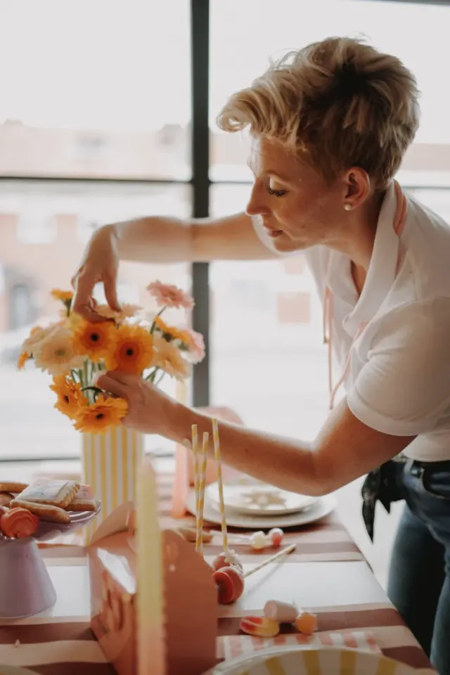 Artisane composant un bouquet de gerberas sur une table dressée, reportage pour Chez Hélène à Quaëdypre