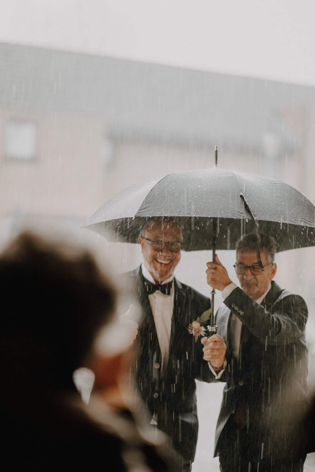Parents d'un marié sous la pluie, parapluie et boutonnière — reportage mariage Flandres