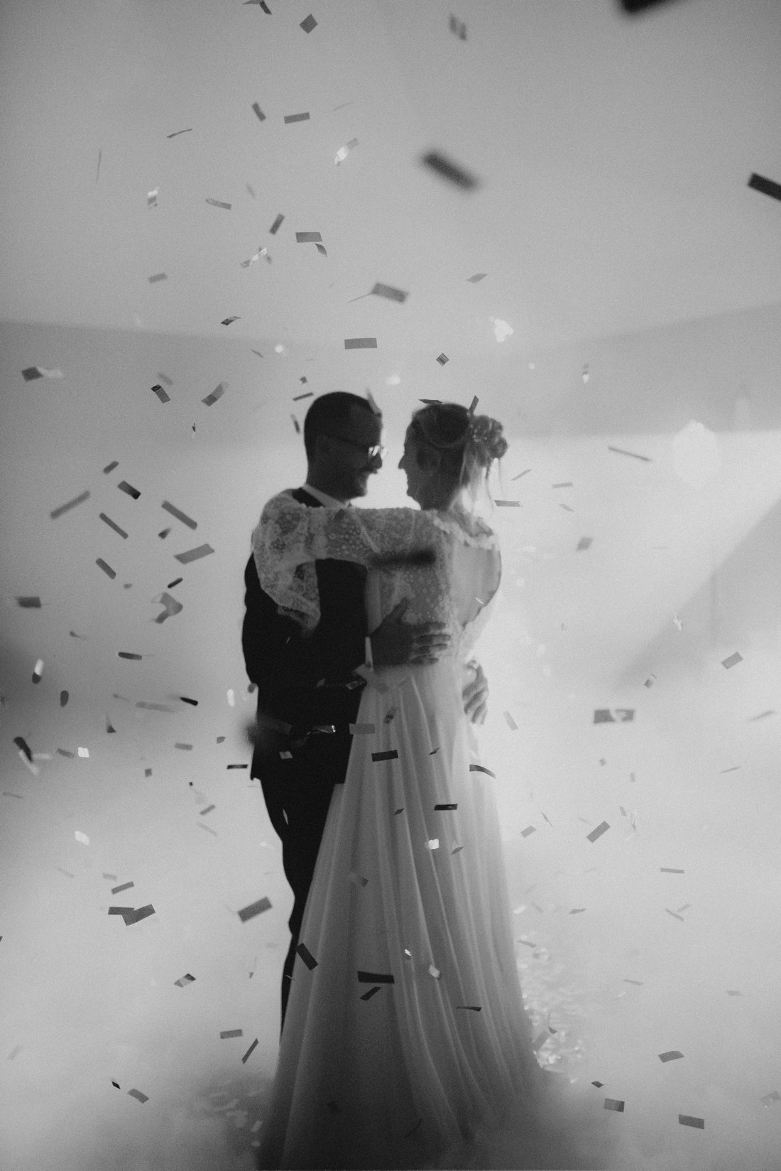 Première danse sous une pluie de confettis argentés en noir et blanc — soirée de mariage
