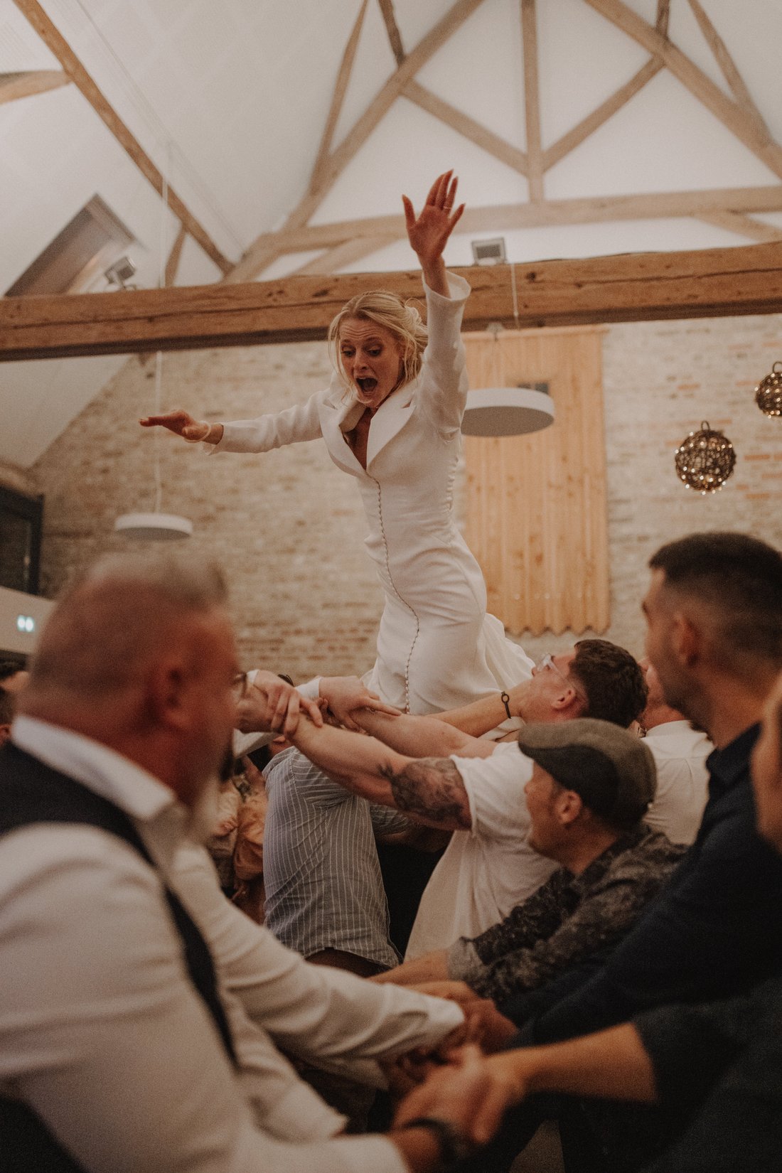 Mariée portée par ses témoins au-dessus de la foule, ambiance grange — soirée festive de mariage